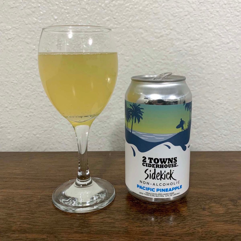 A glass of cider sits next to a can of Pacific Pineapple Sidekick from 2 Towns Cider